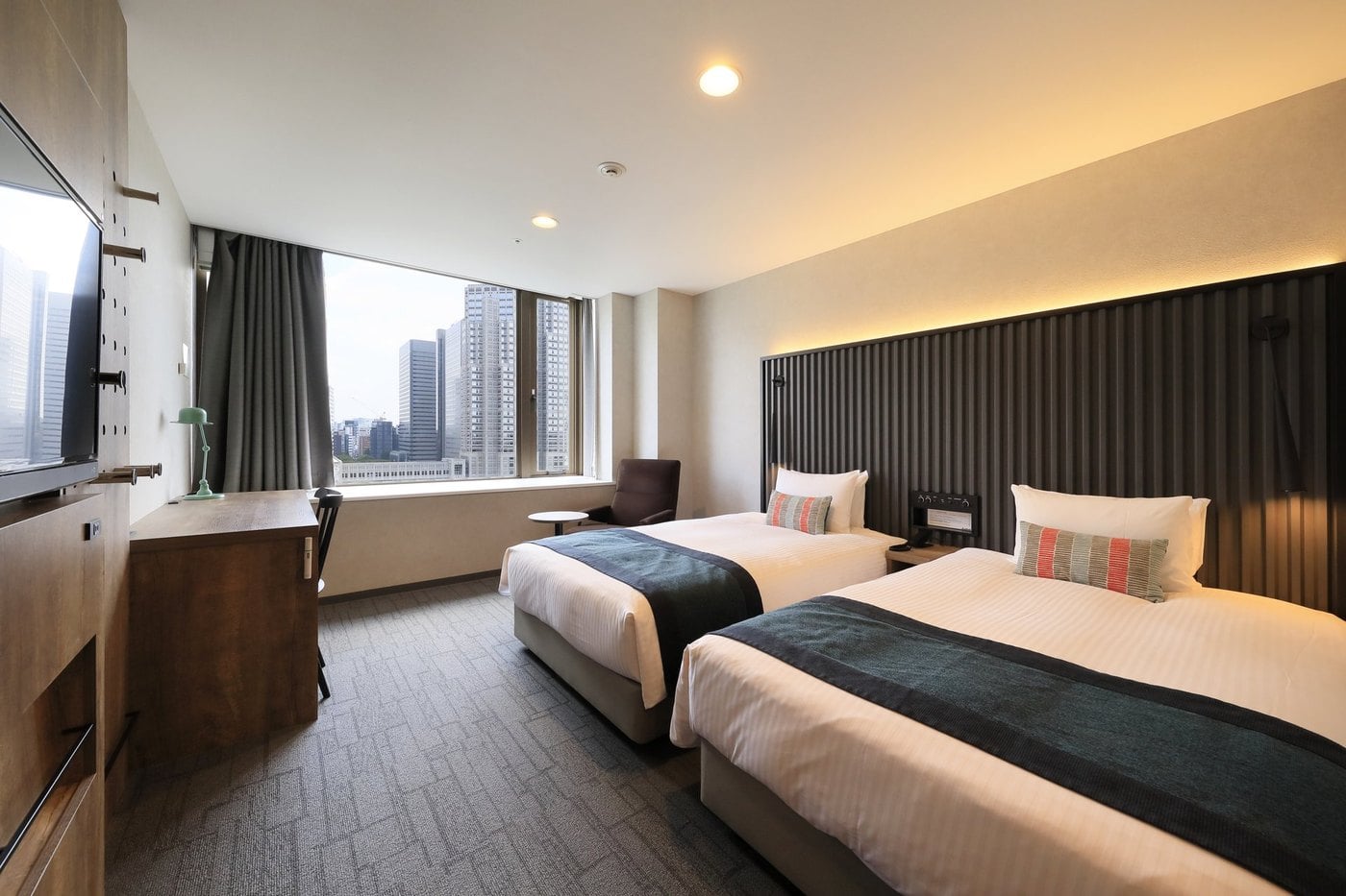A twin room at THE KNOT TOKYO Shinjuku, two separate beds and a view of the Shinjuku skyline