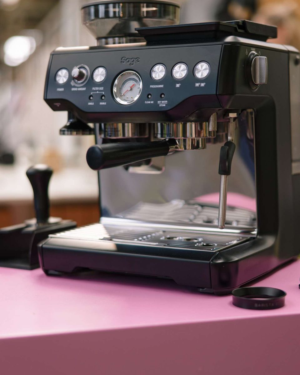 An espresso machine with a built-in grinder on a pink counter at the Sage stand