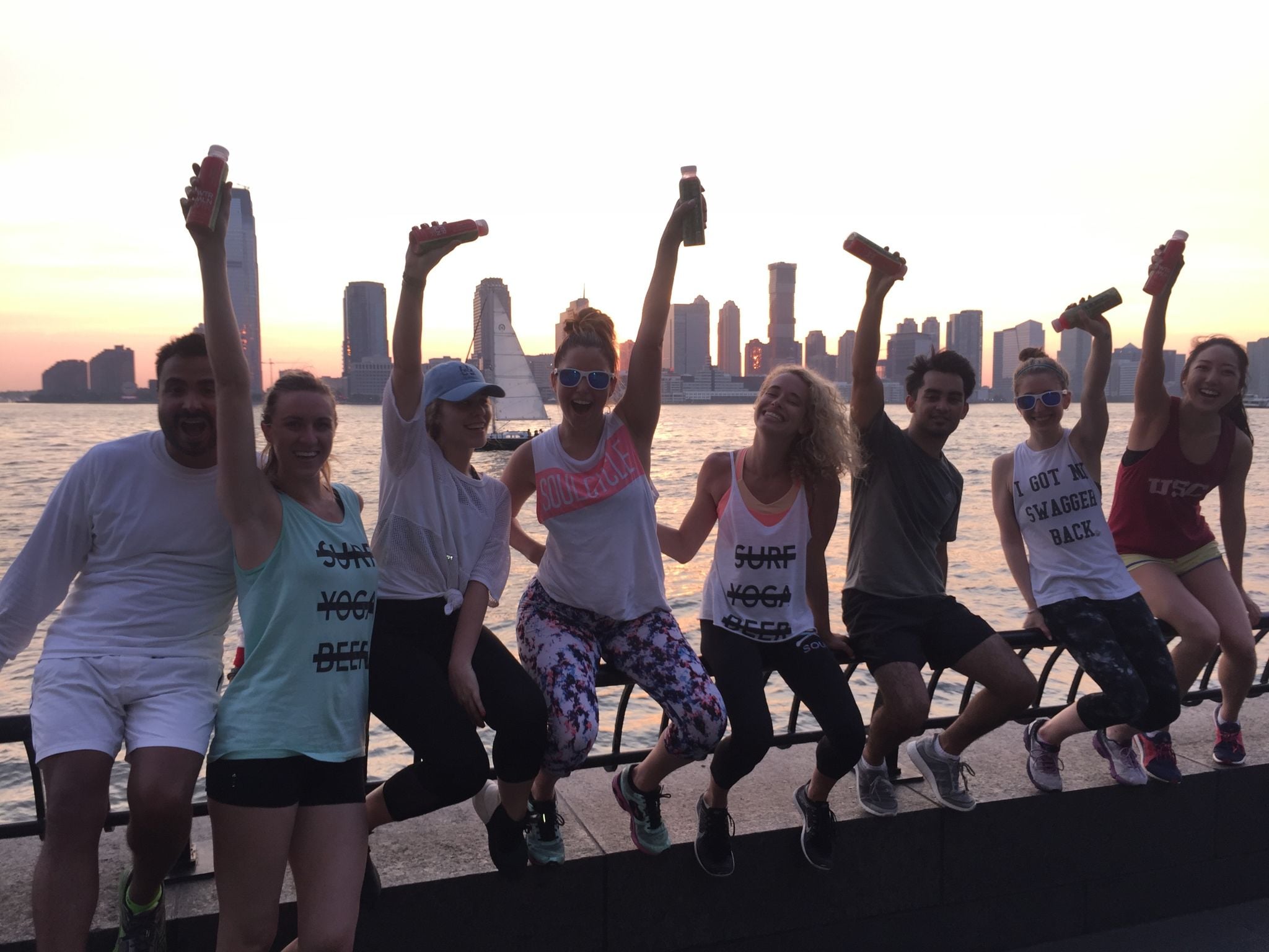 Run club raising a drink over the Hudson at sunset