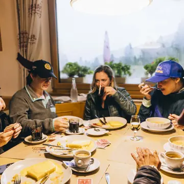Group lunch around a big table in a wood panelled hut on the SYB Dolomites trip
