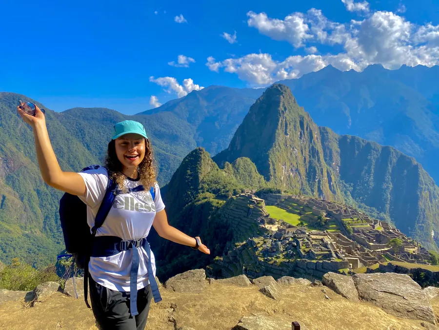 A student with arms out above Machu Picchu