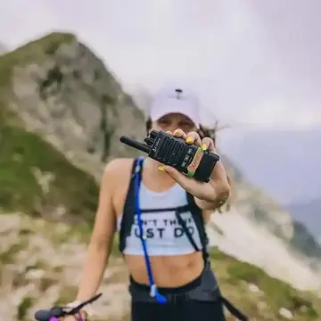 Hiker holding a radio up to the camera on a mountain trail on the SYB Dolomites trip