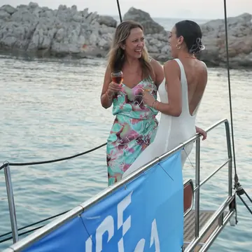 Two friends chatting on deck next to a Surf Yoga Beer flag on the SYB Turkey trip