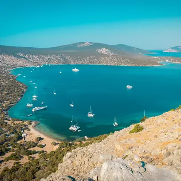 Hilltop view over a turquoise bay dotted with anchored boats on the SYB Greece trip
