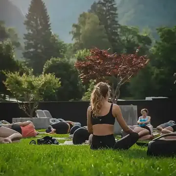 Outdoor yoga class on the grass with trees and mountains behind on the SYB Dolomites trip