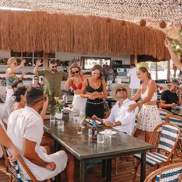 Crew cheering around a long table at a beach club on the SYB Turkey trip