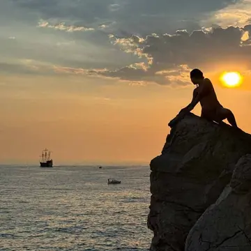 Sitting on a cliff edge at sunset with a ship out on the water on the SYB Croatia trip