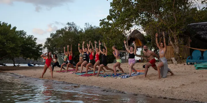Yoga class in a line on the beach at the edge of the water on the SYB Philippines trip