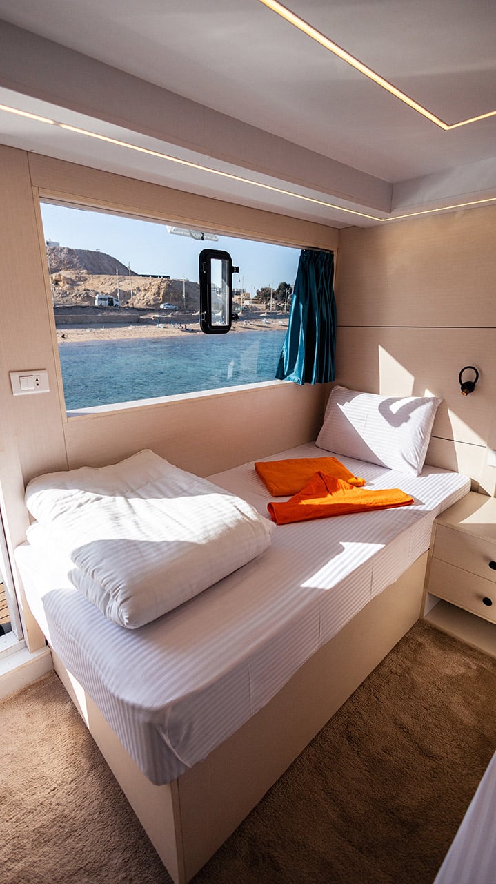 An upper deck cabin with a big window onto the sea