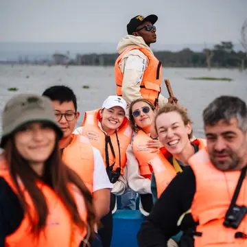 Crew in orange life jackets smiling on a boat ride in Kenya