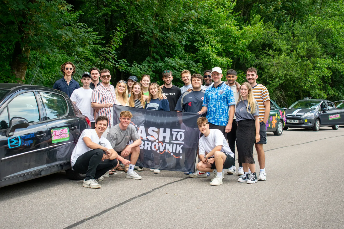 Hardest Adventures team holding a banner on a forest road during the Dash to Dubrovnik.