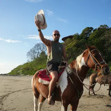 Horseback rider on the beach waving a hat in the air on the SYB Nicaragua trip