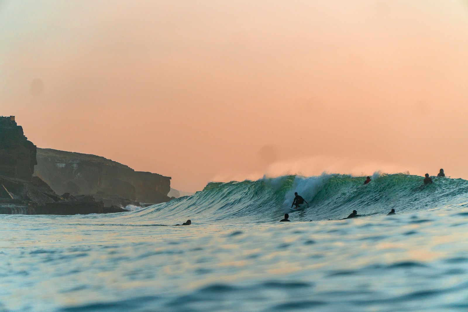 Surfers at sunset under the Algarve cliffs