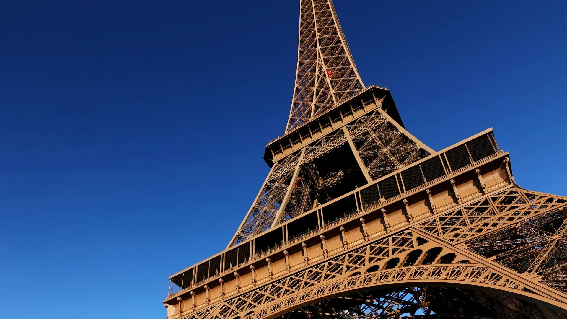 The Eiffel Tower glowing at golden hour against a deep blue sky, the iconic backdrop of the Hardest Adventures Paris Marathon.