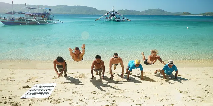 Clap push ups in a row on a white sand beach with boats behind on the SYB Philippines trip