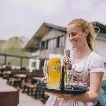 Server in a dirndl carrying a tray of beers at a mountain hut on the SYB Dolomites trip