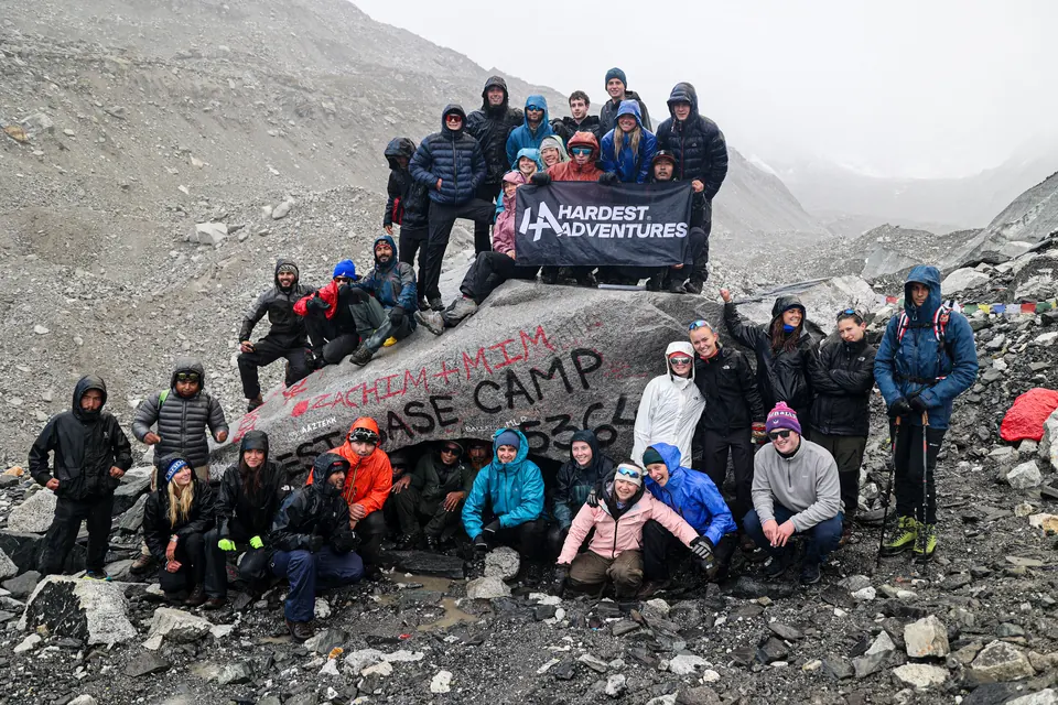 The whole Hardest Adventures group with their banner on the Everest Base Camp rock at 5,364 m