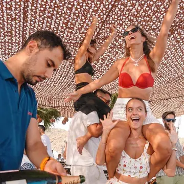 Champagne being poured with friends dancing behind at a beach club on the SYB Turkey trip