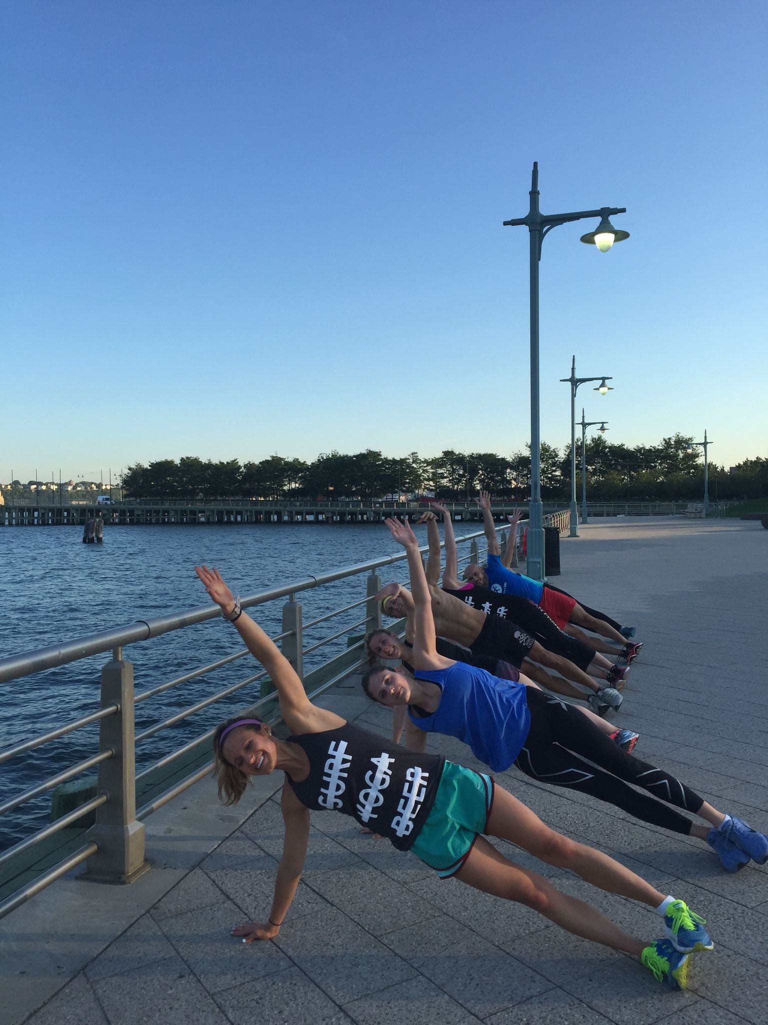 SurfYogaBeer Run Club doing plank holds on the Hudson River esplanade