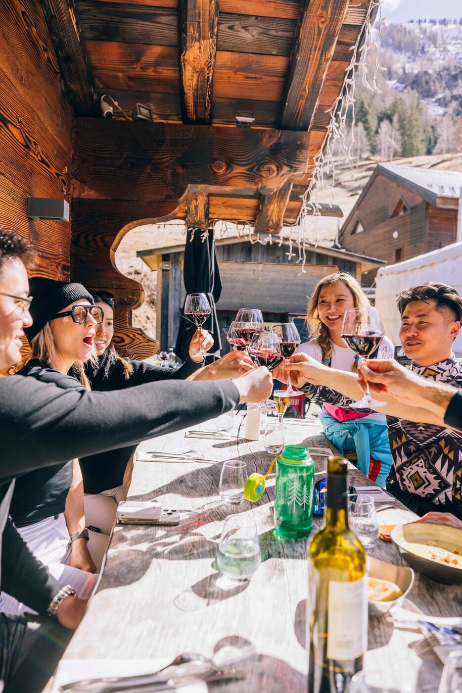 SYB travelers toasting over lunch at a long table in a mountain restaurant