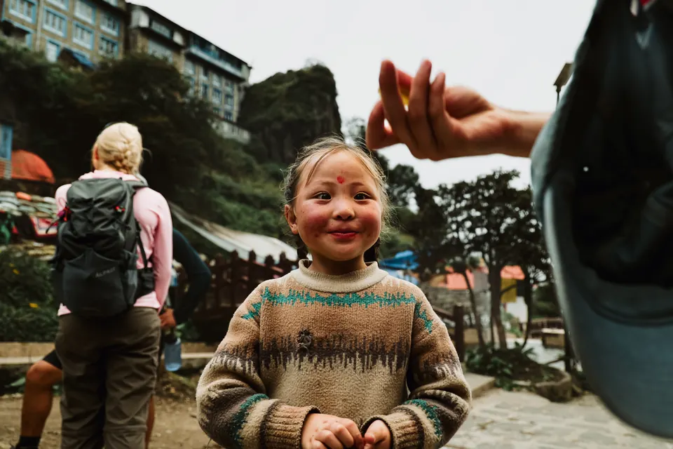 A young Sherpa girl grinning at a trekker on arrival in Namche Bazaar