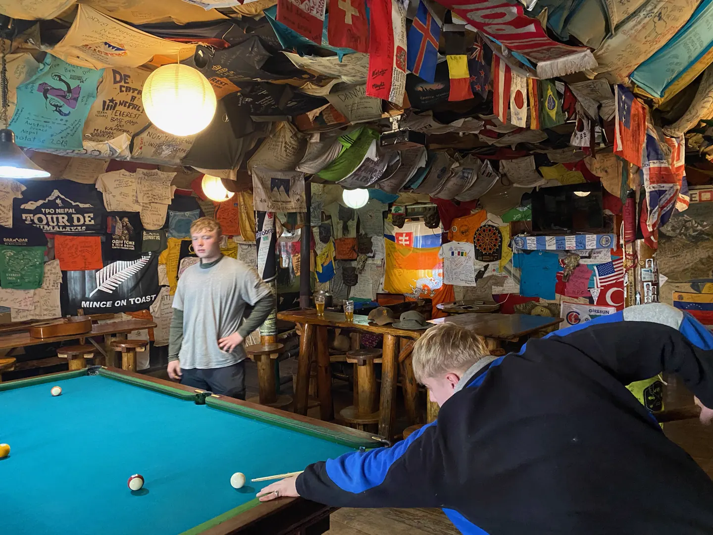 Trekkers playing a game of pool in a Himalayan teahouse on the Everest Base Camp trek with Hardest Adventures.