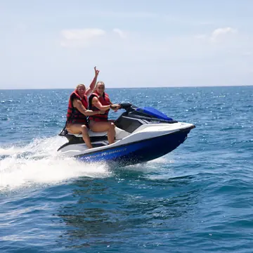 Two people riding a jet ski across open water on the SYB Bali trip