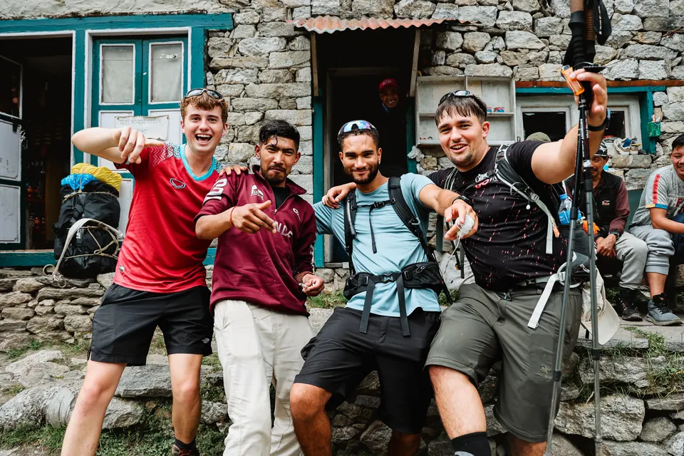 Trekkers and their Nepali guides posing outside a stone teahouse on the trail to Tengboche