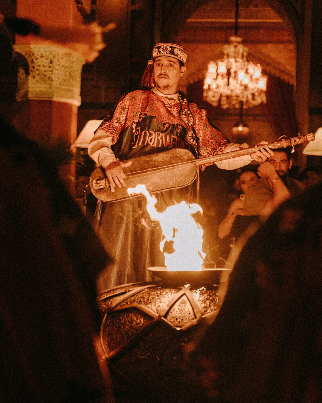 Gnawa musicians playing around a fire at night in the Moroccan desert