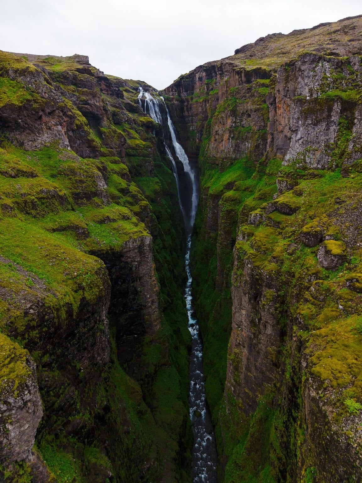A waterfall dropping into a mossy canyon in the west of Iceland
