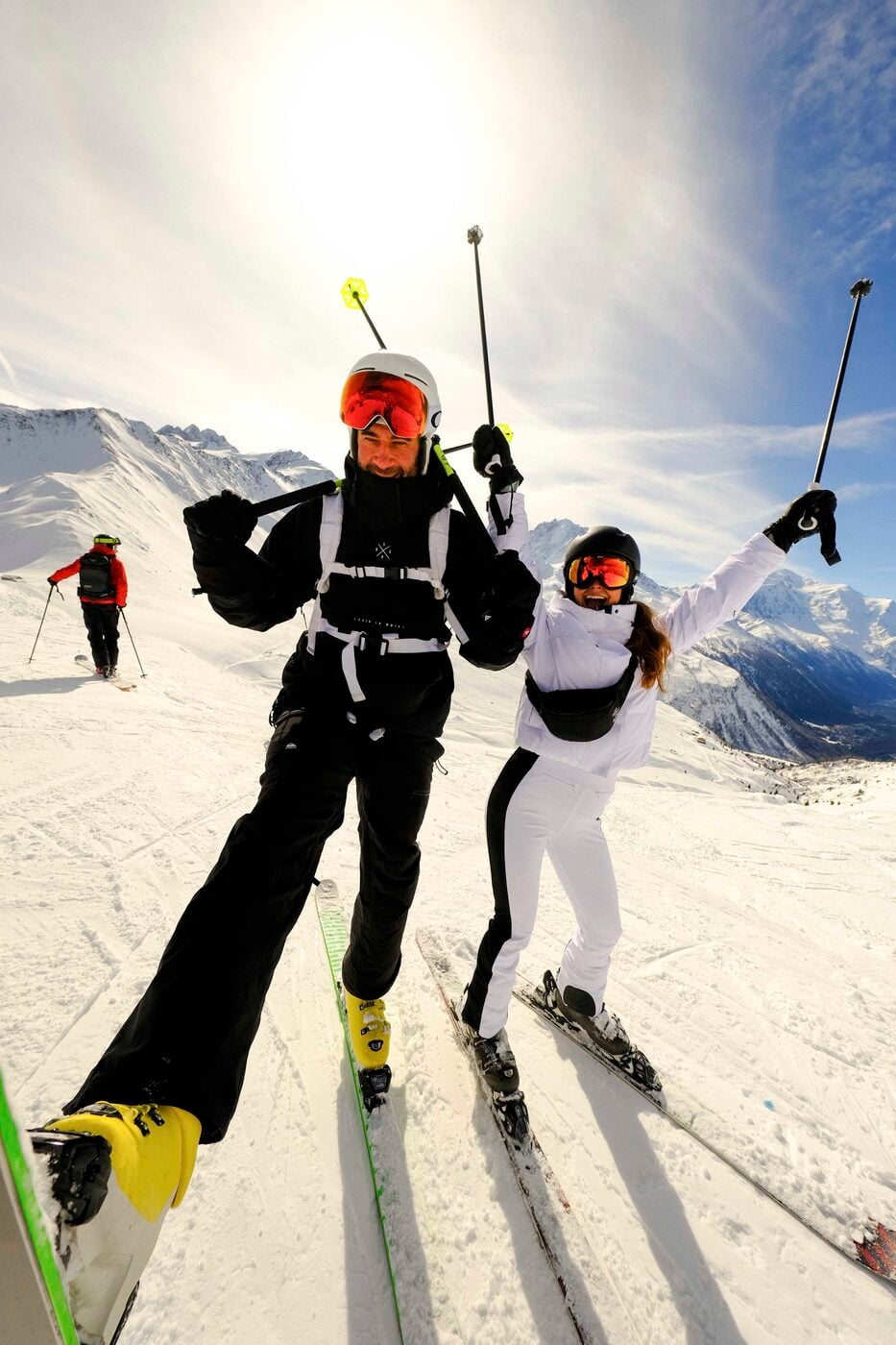 Two skiers on the slope with the sun behind them