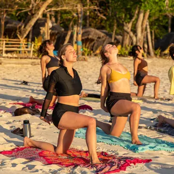 Low lunge on the sand in a golden hour yoga class on the SYB Philippines trip