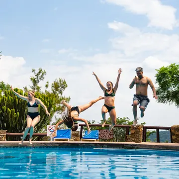Four friends jumping into the pool on the SYB Kenya trip