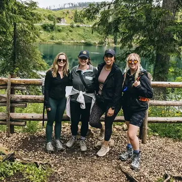 Four hikers by a fence above a forest lake on the SYB Dolomites trip