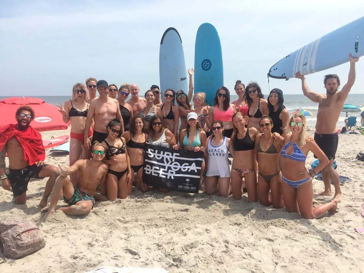 SurfYogaBeer guests carrying surfboards on the beach in Nicaragua