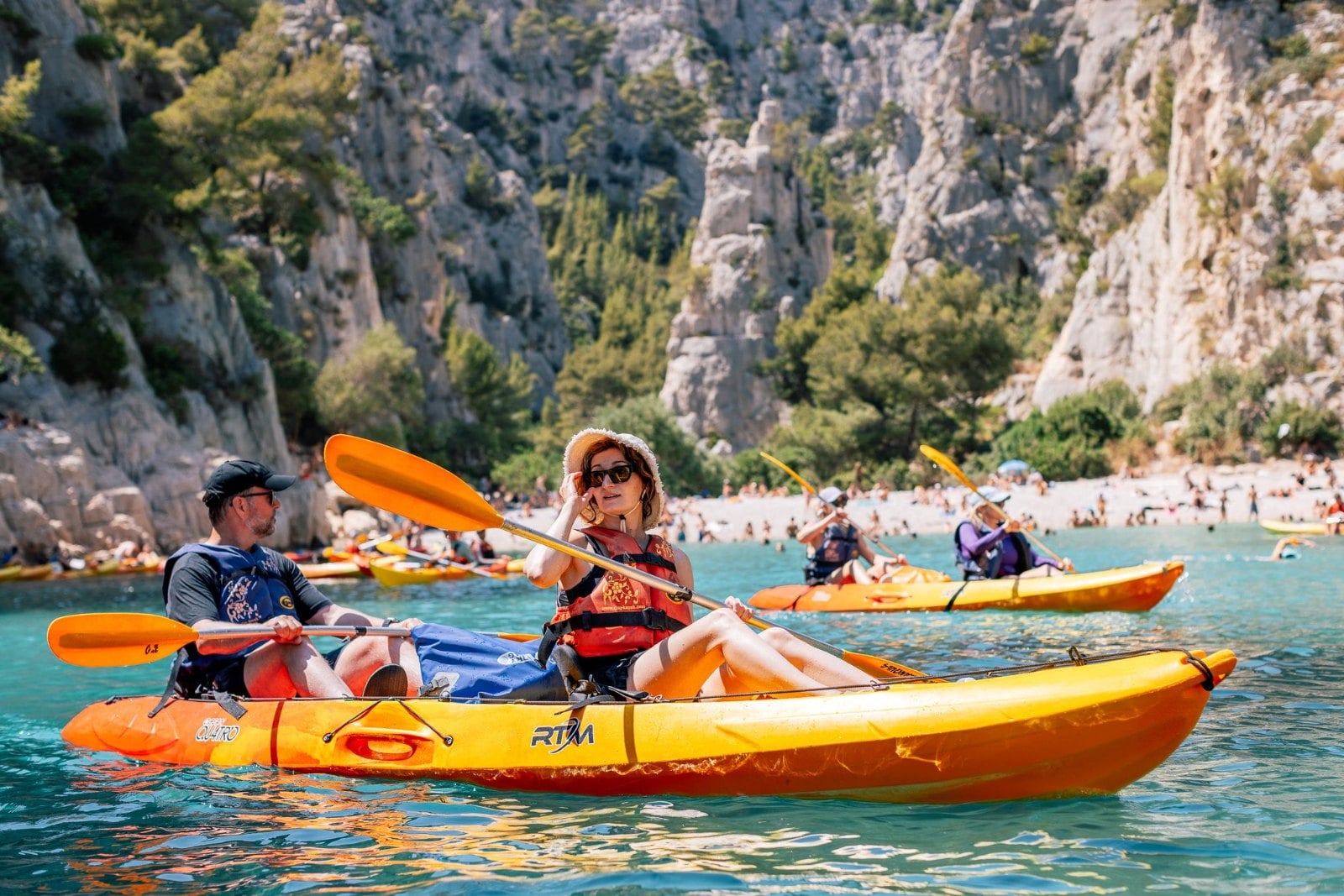 The SurfYogaBeer crew paddling kayaks into a turquoise calanque near Cassis
