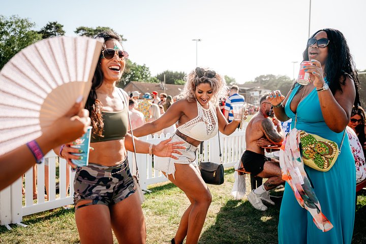 Women dancing in the sun outside in the beer garden of the V.VIP arena at Bournemouth 7s Festival watching the rugby, in Dorset England