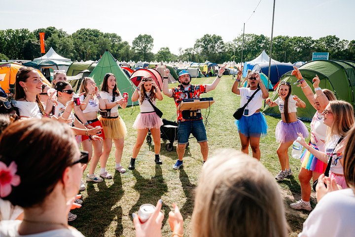 Roaming campsite DJ in camping with a large group of girls dancing in the sun at Bournemouth 7s Festival, in Dorset, England.