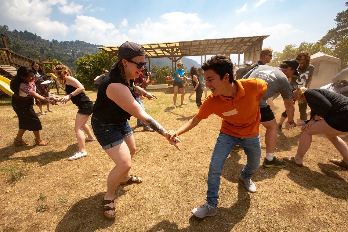 Participant and local community member joyfully dancing together during the Guatemala Impact Marathon, highlighting cultural exchange and community connection in a beautiful rural setting.