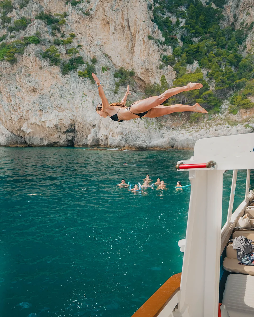 A traveler diving off a boat by the cliffs of the Amalfi Coast