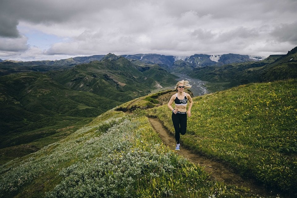 A runner on a ridge trail through green hills in the Icelandic highlands