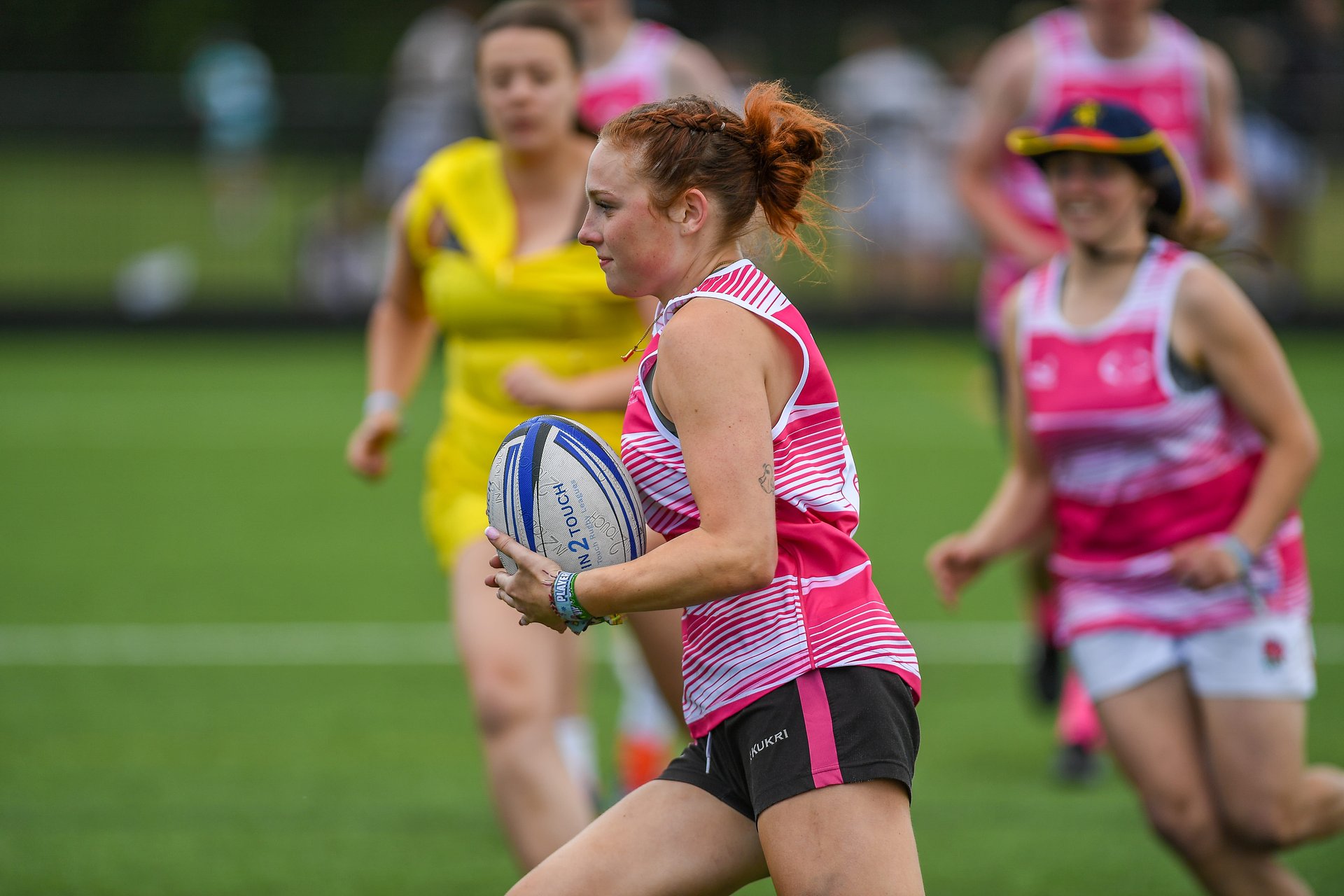 Mixed touch rugby player runs with the ball being chased at Bournemouth 7s Festival, Dorset.