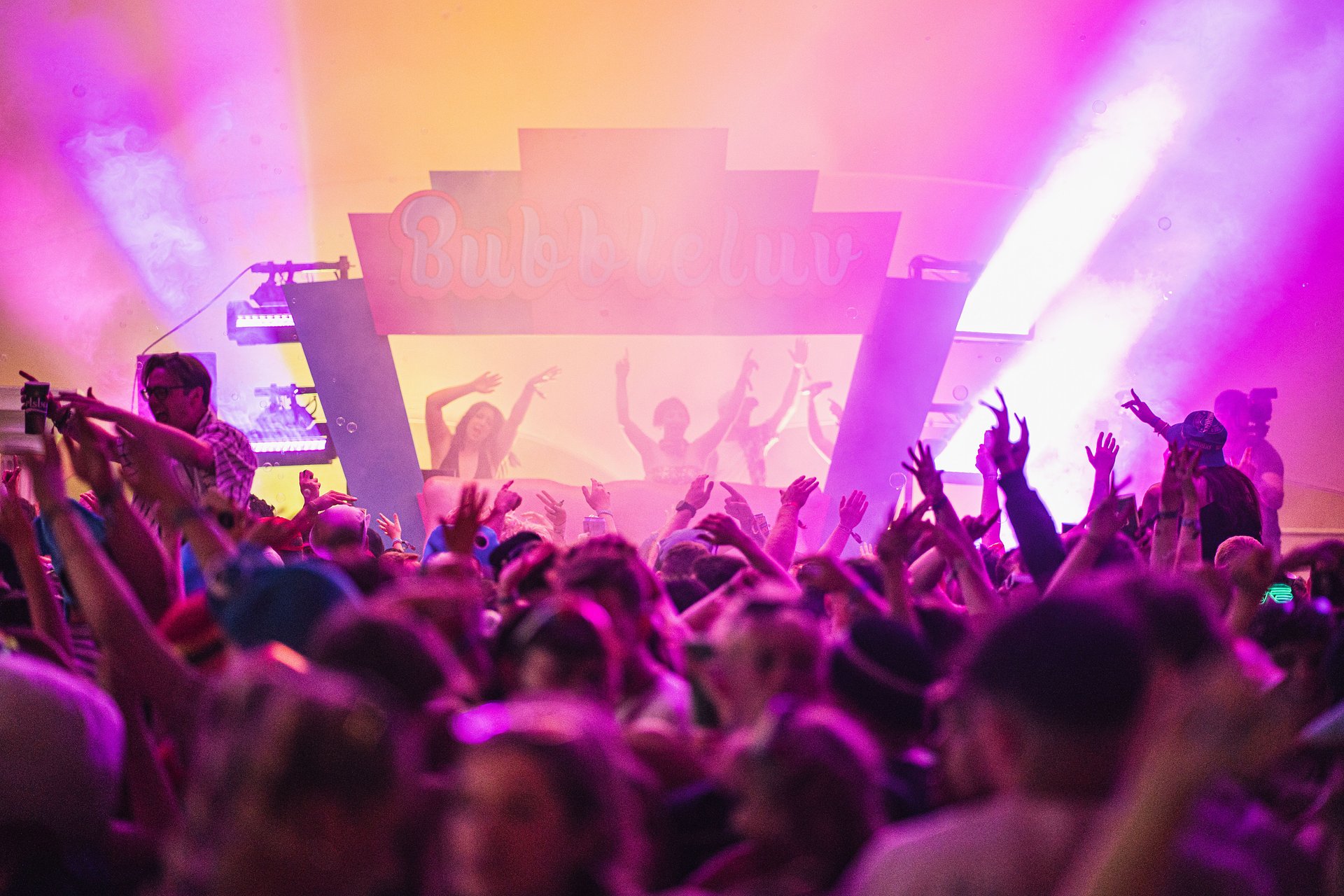 Bubbleluv music arena with a large crowd waving their hands in the air as the DJs perform on stage at Bournemouth 7s Festival, in Dorset.