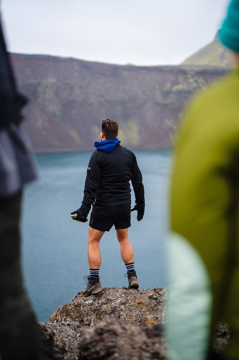 A hiker standing on a rock above a crater lake in Iceland
