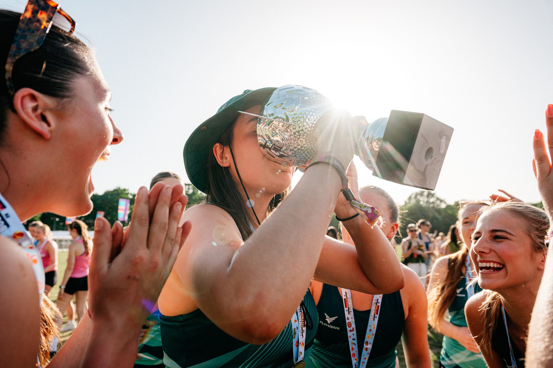 Netball team celebrating drinking from a trophy after competing at Bournemouth 7s Festival in Dorset.