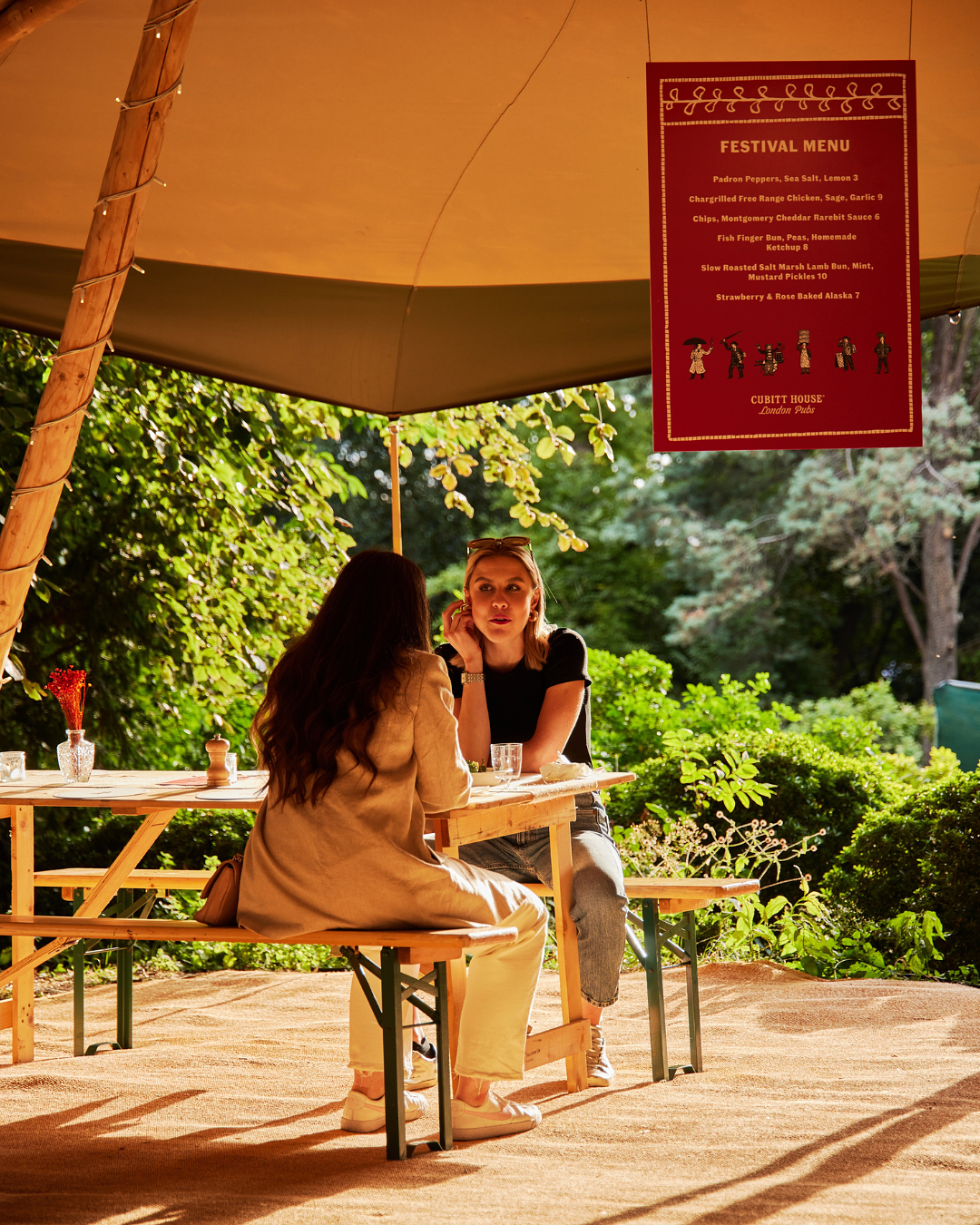 Girls sitting inside sunny tipi waiting for their mouthwatering dishes from Cubitt House at Savour festival 2023