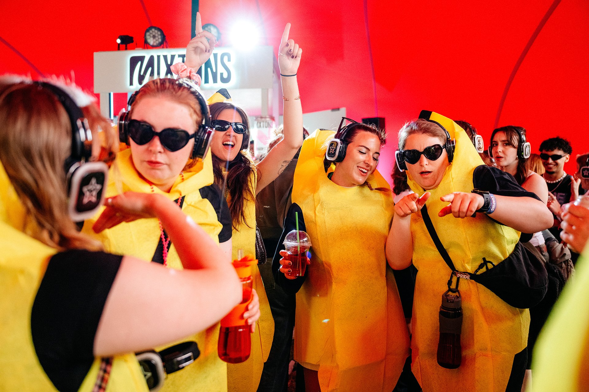 Group of girls dance in fancy dress banana costumes in the Silent Disco arena at Bournemouth 7s Festival in Dorset