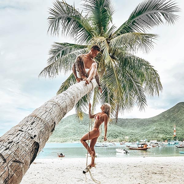 Thailand tour group_couple hanging on palm tree in koh tao