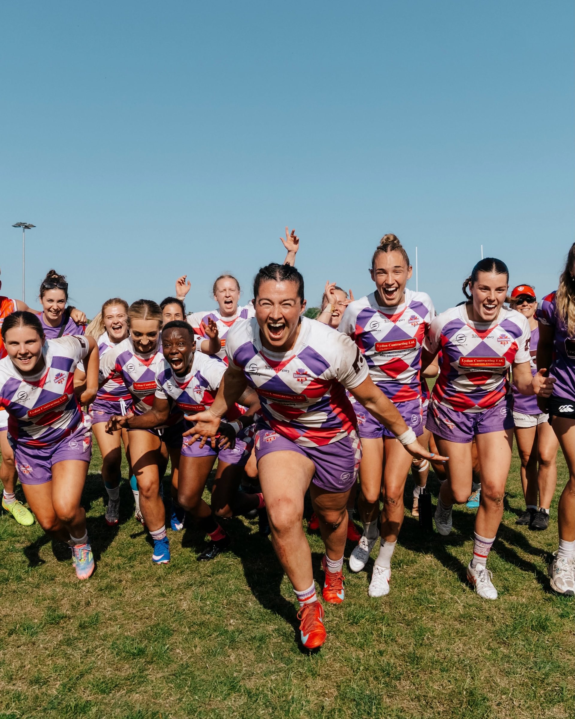 Women’s rugby team celebrating together on the pitch at Bournemouth 7s Festival in Dorset.