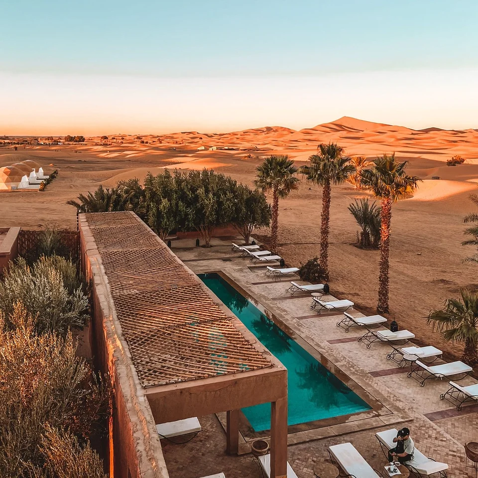A lodge with a pool at the edge of the dunes, seen from above